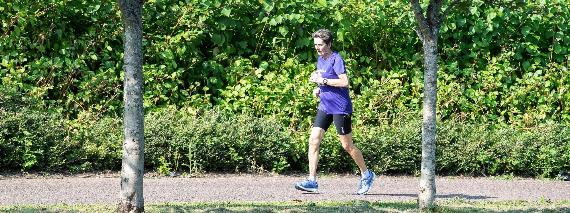 Person running along path between trees