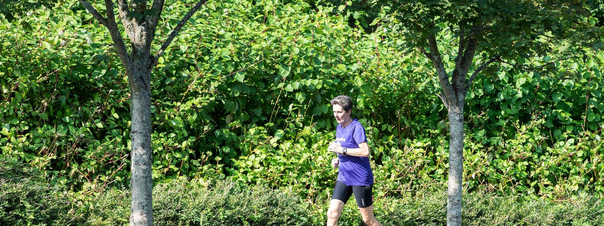 Person running along path between trees