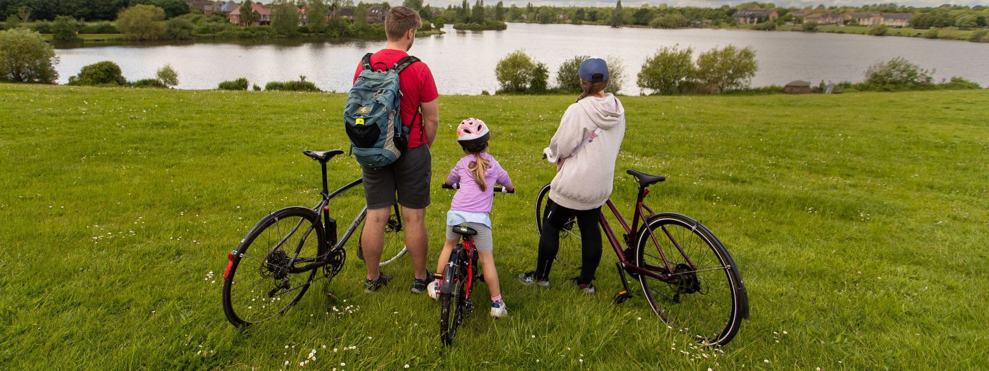 A family on bikes facing towards Furzton Lake