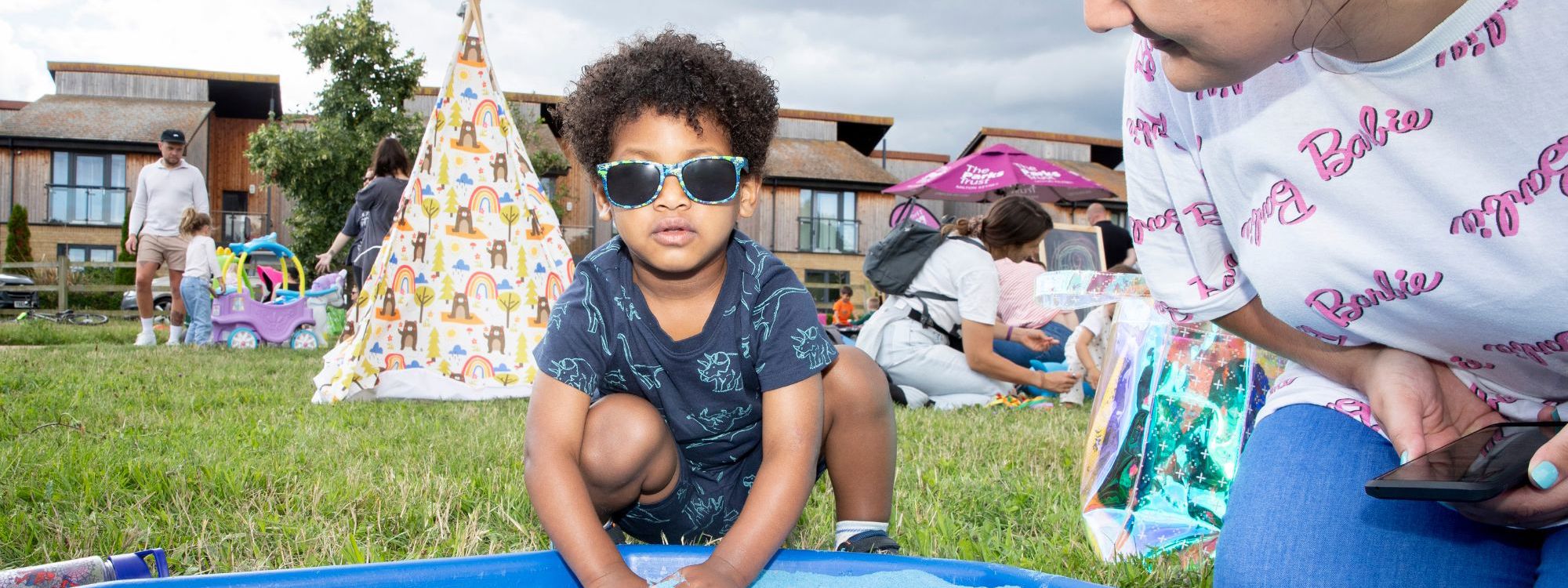 Child playing in the sandpit with parent at event in the park