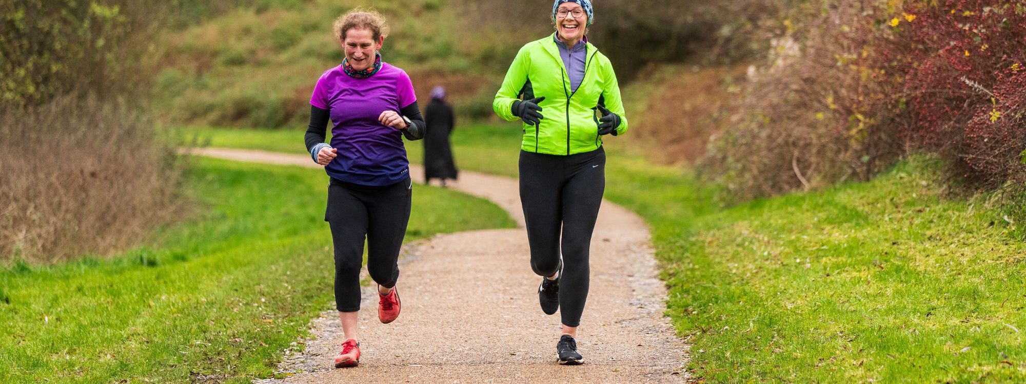 Two people running along pathway in a park