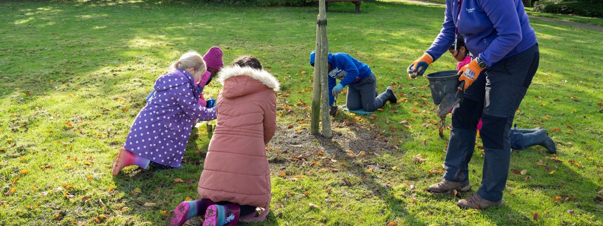 Children planting bulbs in the park with The Parks Trust outdoor learning leader