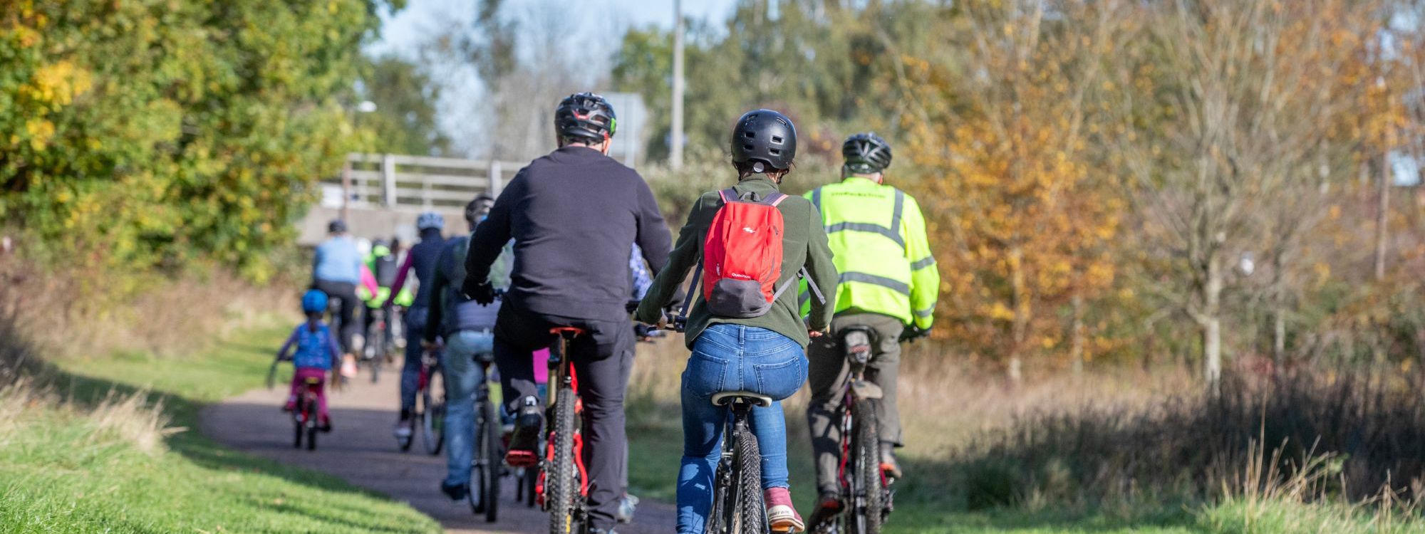 Group of people cycling down pathway in the park