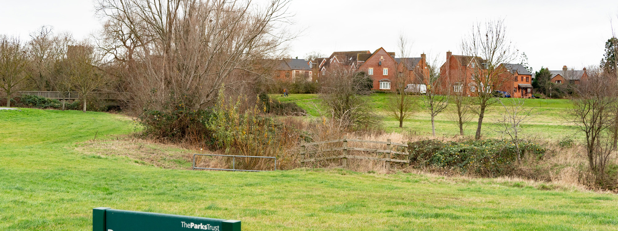 Houses, pond and park sign at Broughton Brook. 