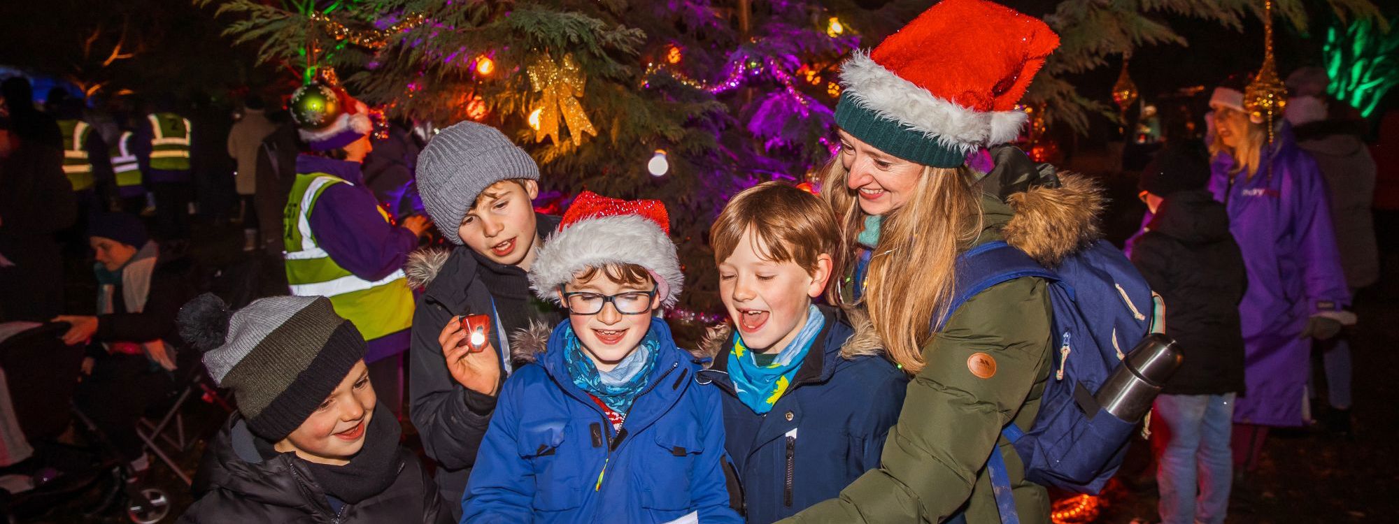 Family signing carols with Christmas tree in the background