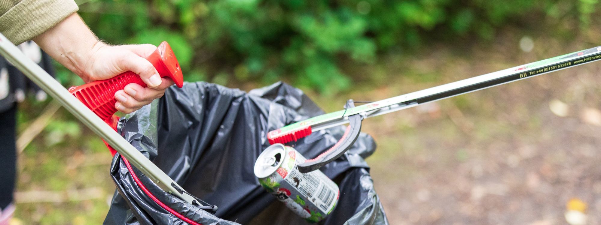 Litter pickers picking up can and dropping into black bin bag