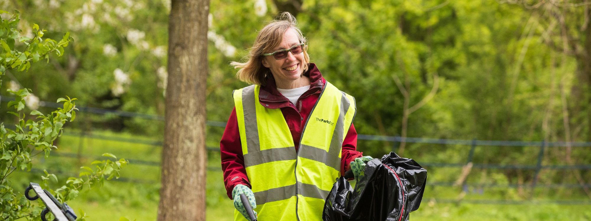 Person litter picking in the park holding waste bag