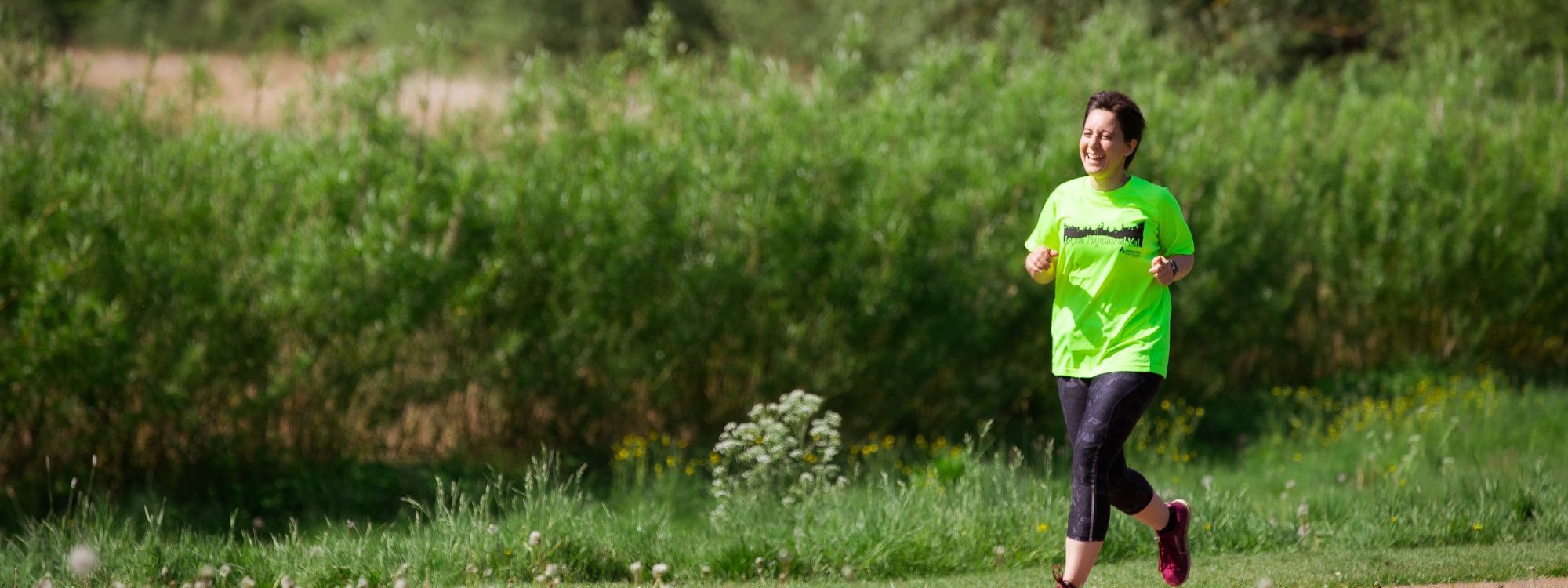 Person wearing yellow T-shirt running through the park