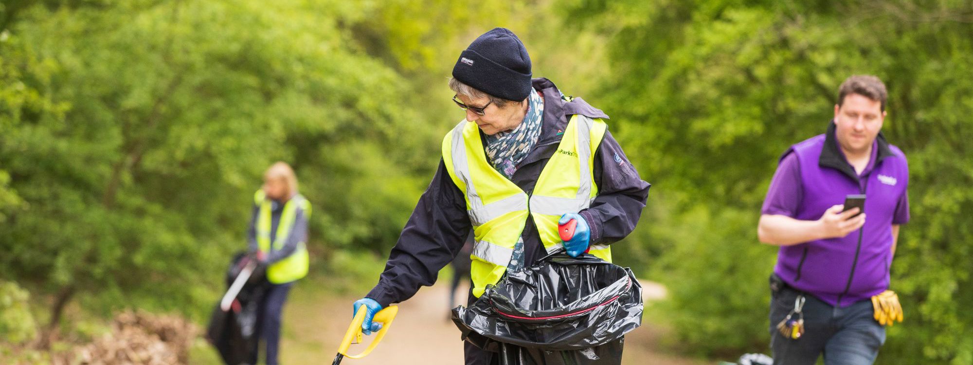 Person litter picking in a park wearing a high vis jacket