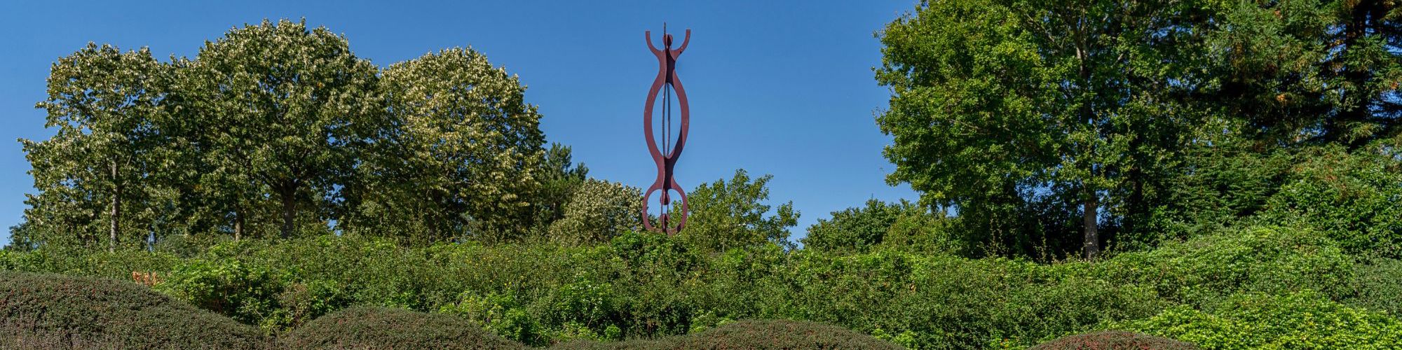 Chain reaction sculpture behind trees next to Campbell Park