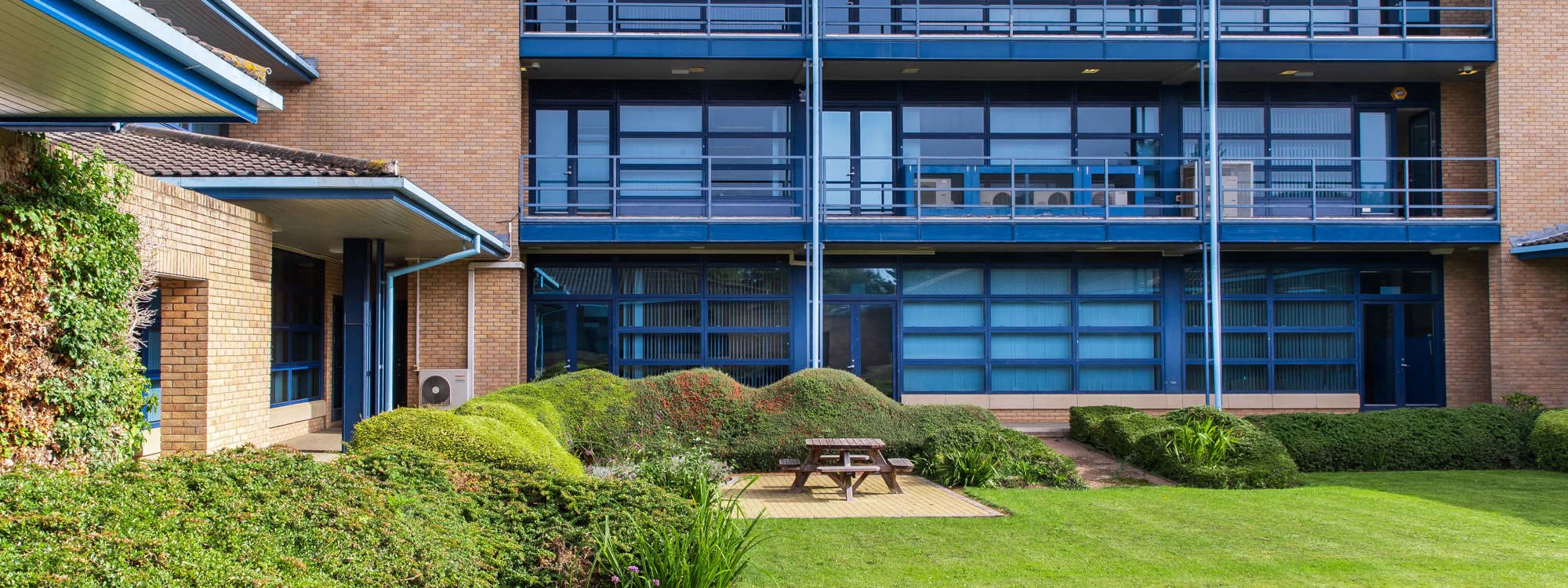 A courtyard garden for office workers, with lawn and picnic bench