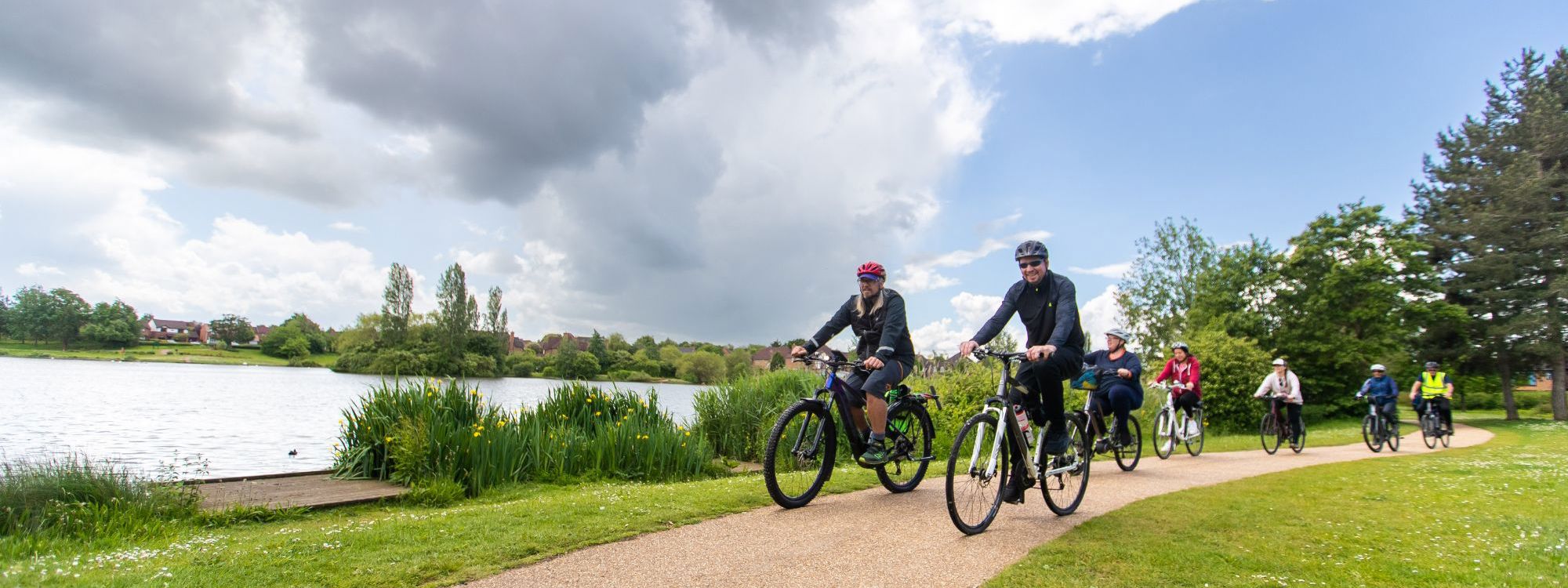 Group of people cycling next to a lake 