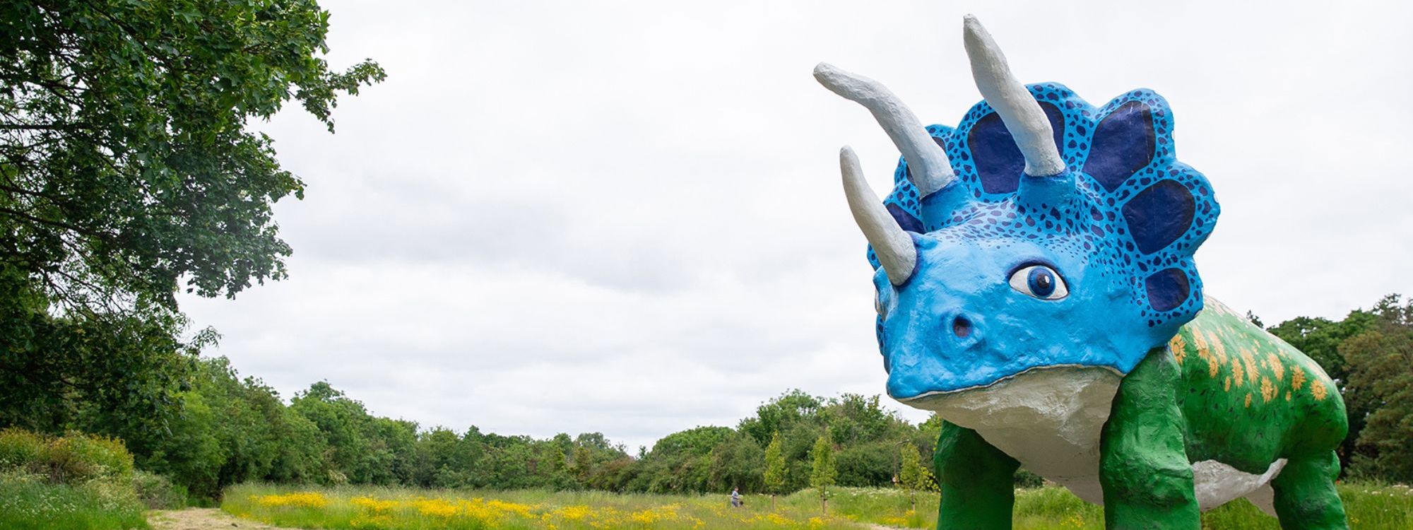 Triceratops sculpture in blue, green and yellow in the park