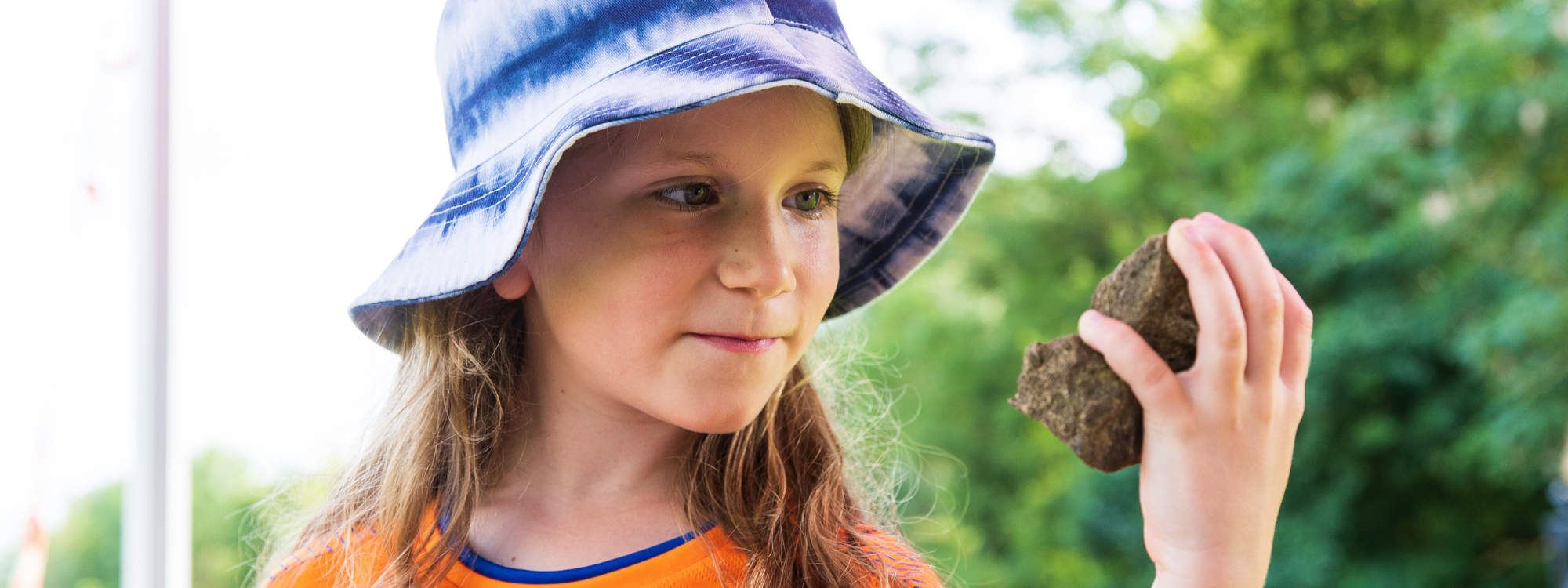 child looking at rock in her hand