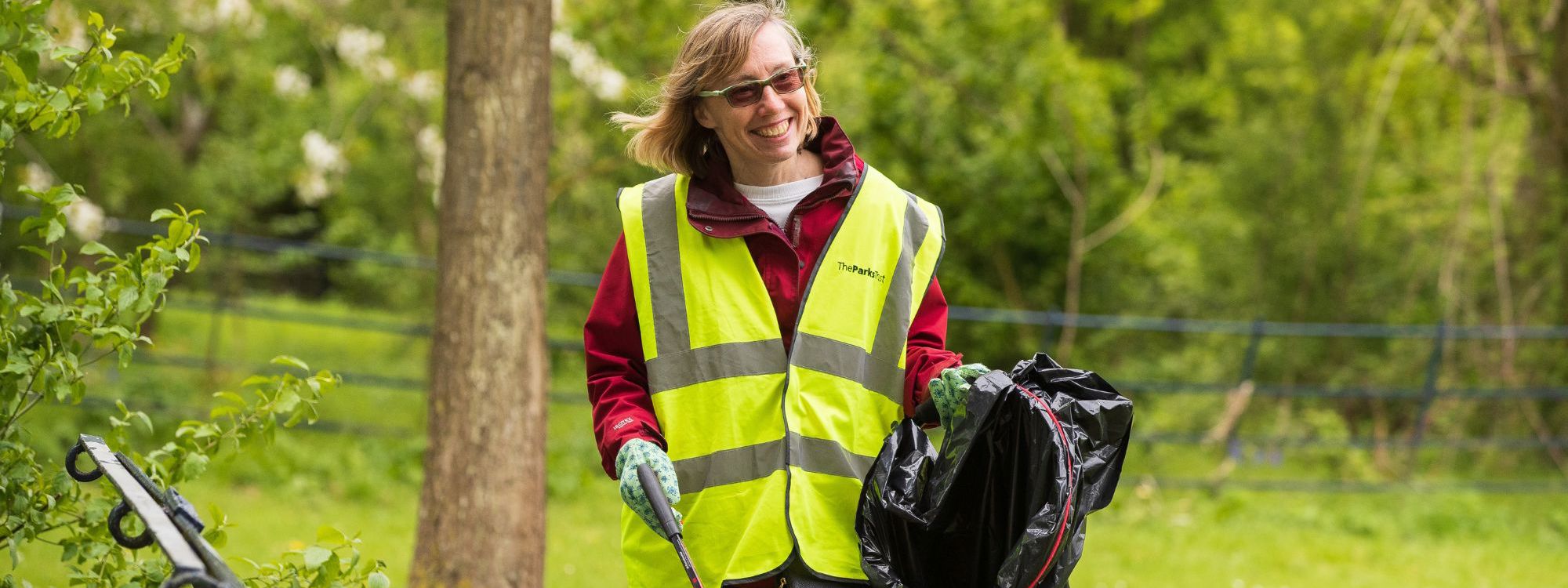 Person smiling and holding litter picker and bin bag