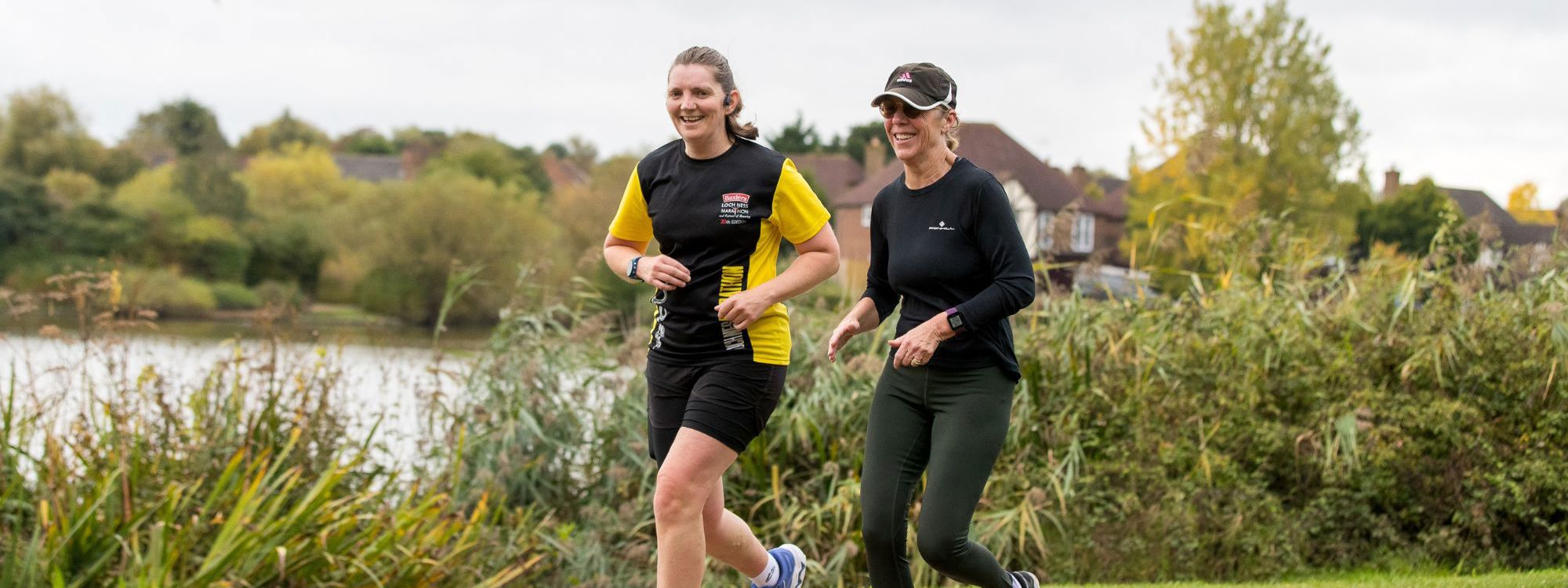 Two people running next to a lake in Milton Keynes