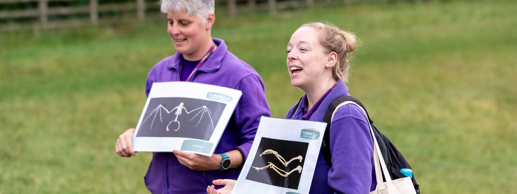 Two Parks Trust Outdoor Learning Leaders holding teaching resources in the park