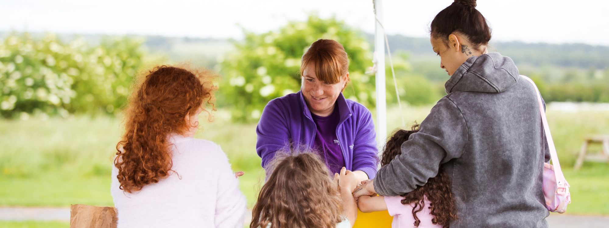 Parks Trust member of staff in purple speaking to family at stand