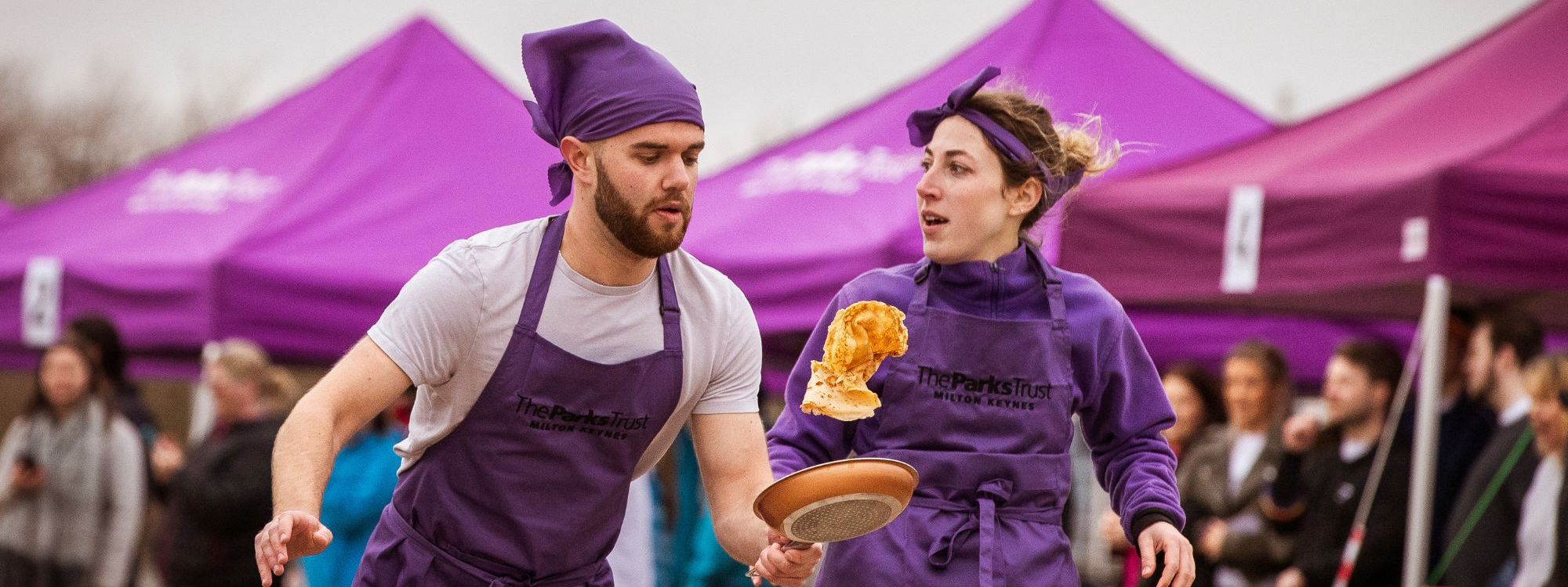 Team competing in Pancake Day race in purple aprons and bandanas 