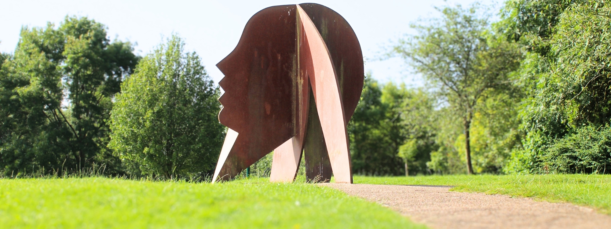 a large metal head made of metal, it is a copper colour as you walk around the piece the head becomes almost 3D as a second head is slotted through the middle of the first