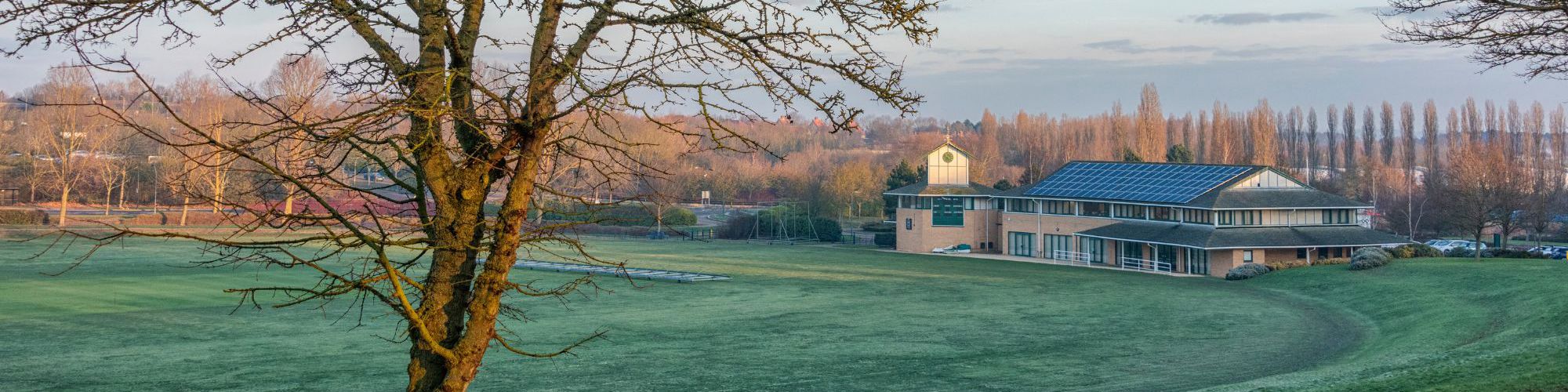 Campbell Park Pavilion Office with tree and cricket pitch in winter