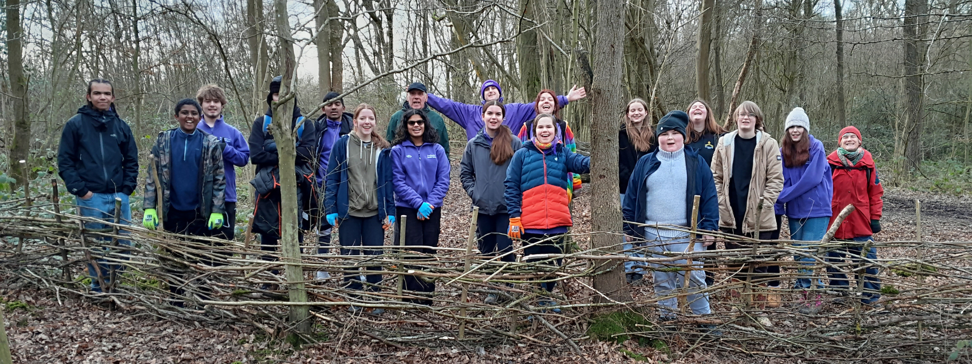 A group of teenagers stood in the woodland smiling at the camera